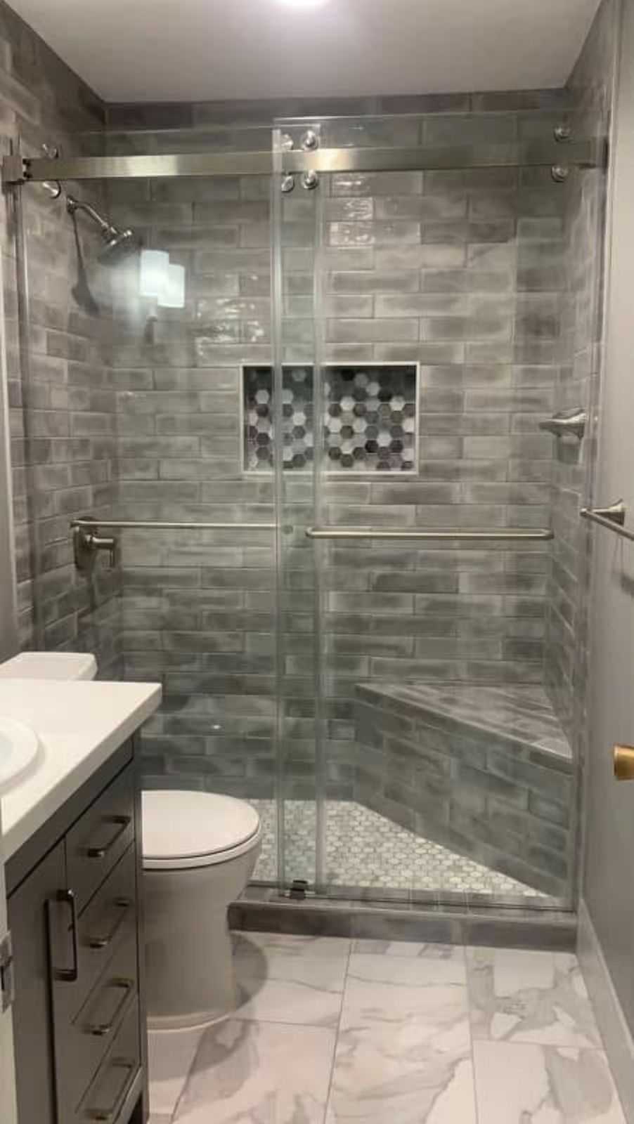 Gray tile walk-in shower with bench and glass door