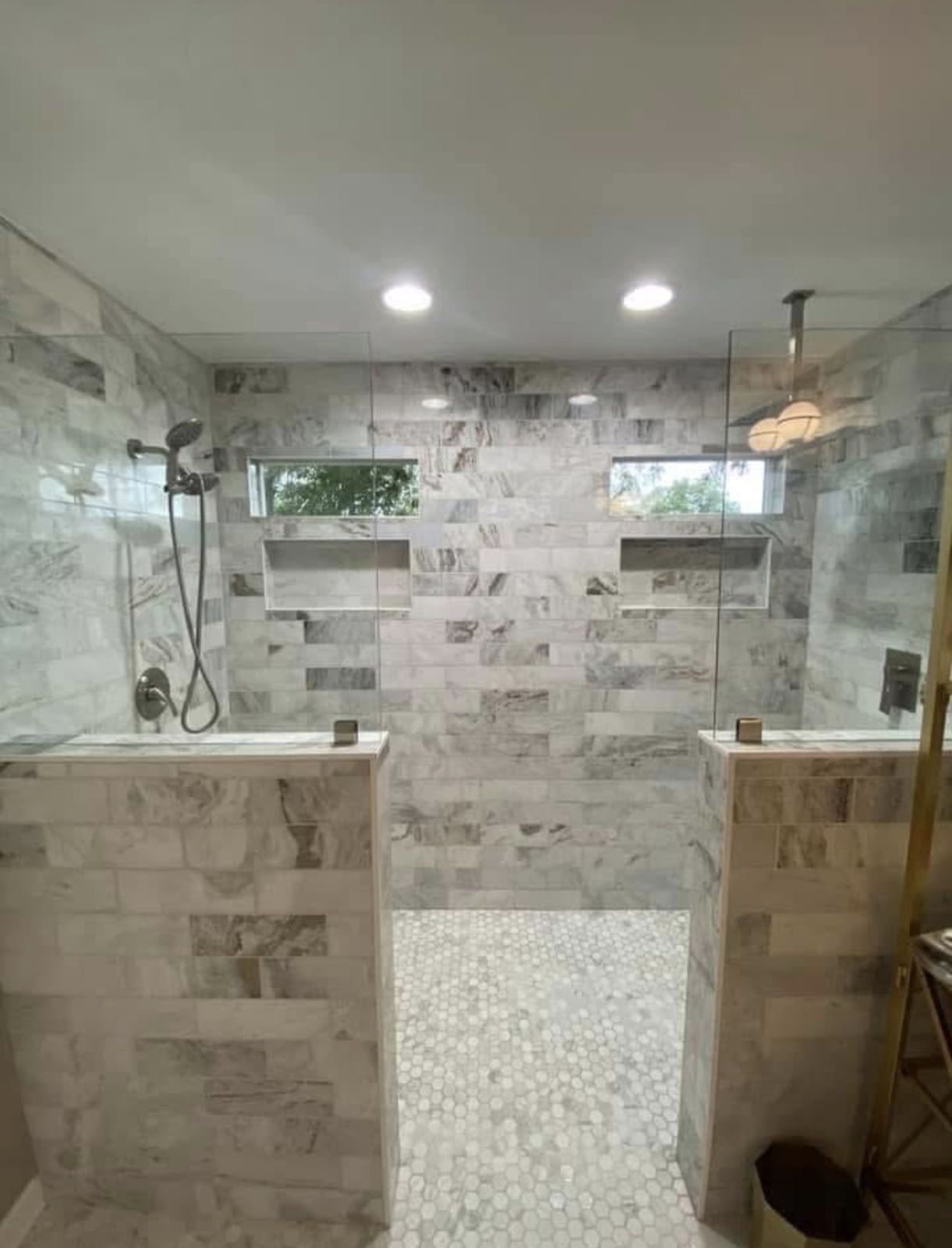 Open walk-in shower with marble tile and pebble floor