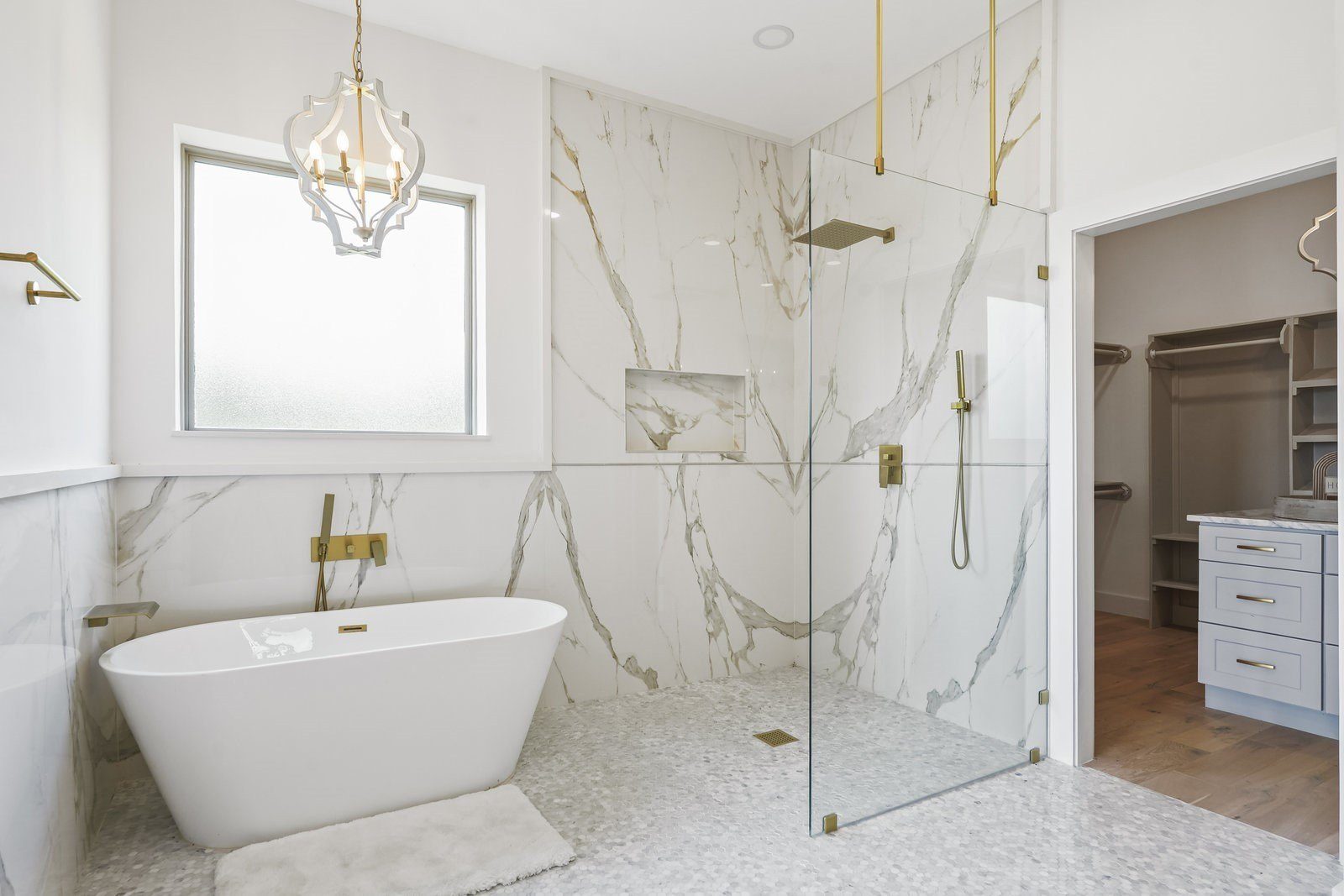 Primary bathroom with a freestanding tub, gold fixtures, chandelier and frameless glass walk-in shower