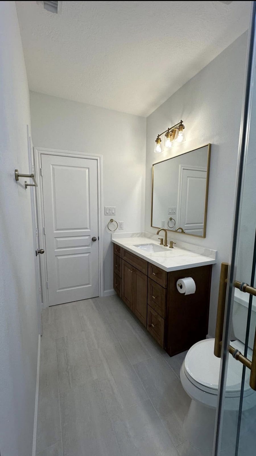 Bathroom with warm wood vanity and gold fixtures